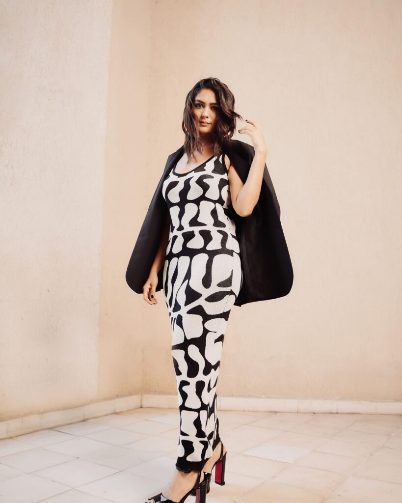 A woman in a black and white patterned dress posing for a photo.