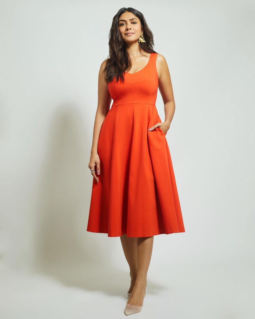 A woman is posing in an orange dress.