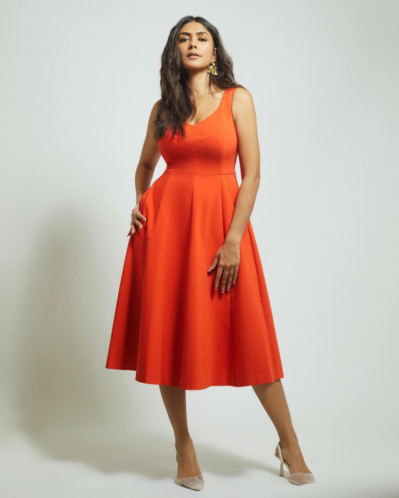A woman in an orange dress posing for a photo.