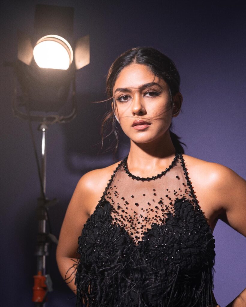 A woman in a black dress posing in front of a light.