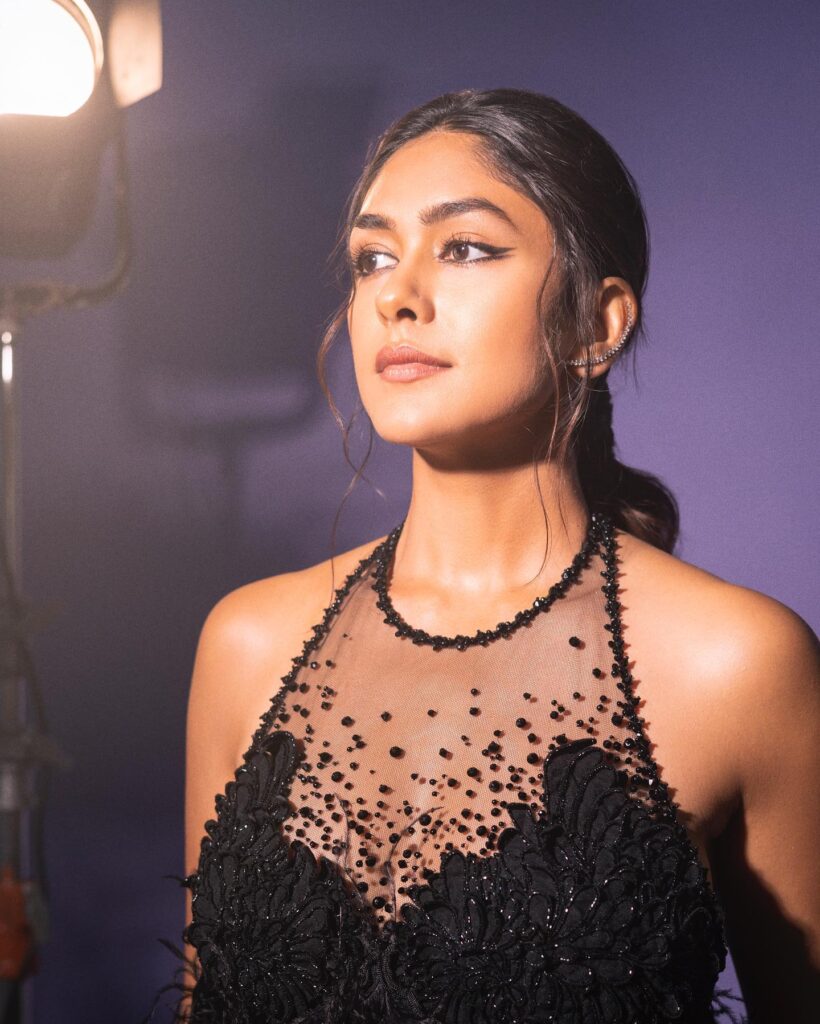 A woman in a black dress posing in front of a camera.